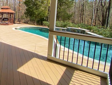  view of a paved backyard, pergola, and pool from deck