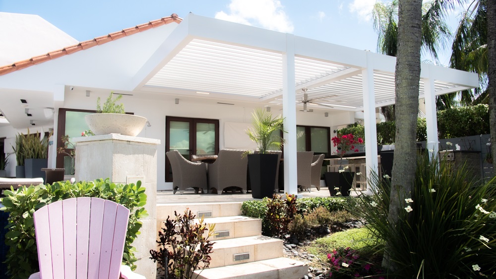 Newly built white pergola over a large deck behind a small white home.