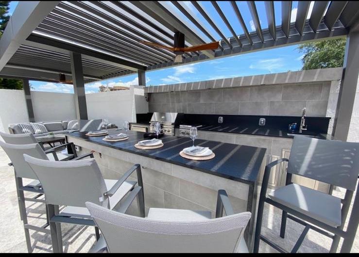 An outdoor kitchen with granite countertops and stainless steel appliances