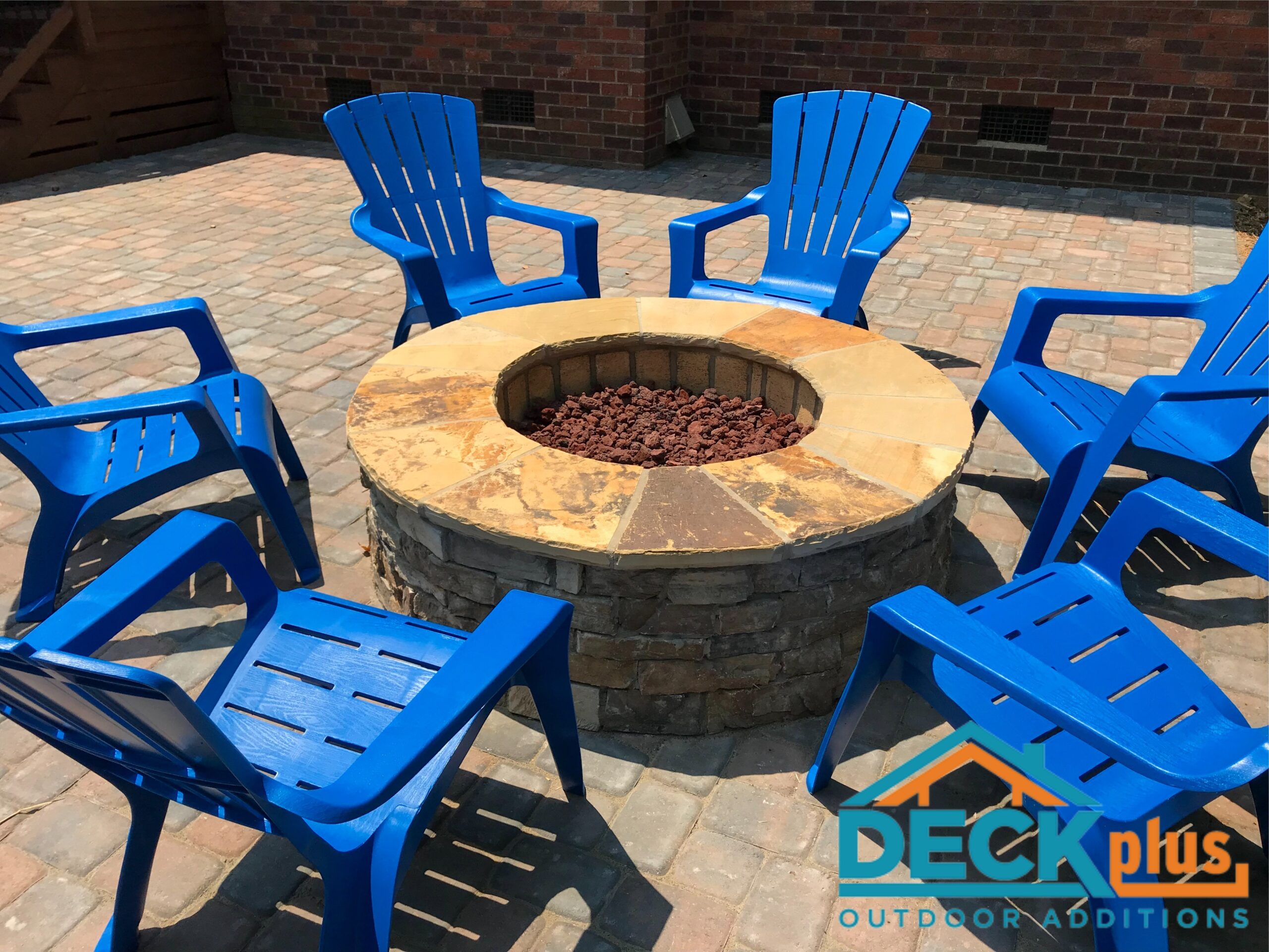 An outdoor fireplace with blue adirondack chairs