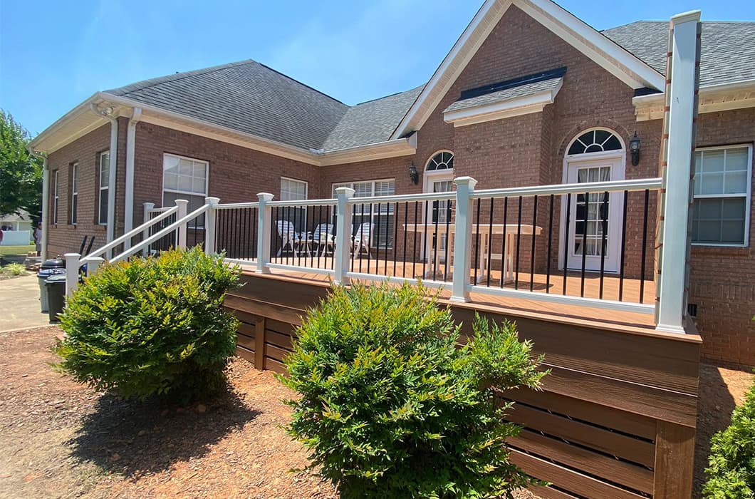 A stained wooden deck with white railing