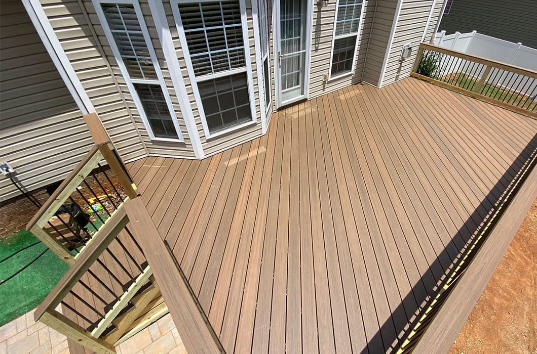 A wooden deck with a railing and a patio area