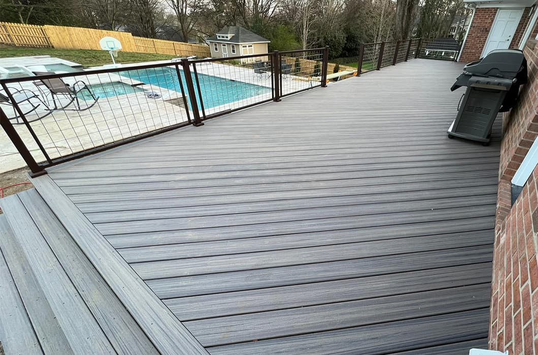 A gray-stained wooden deck with wire railing