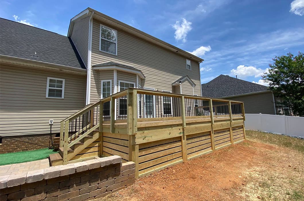 A wooden deck with stairs leading onto a stone patio