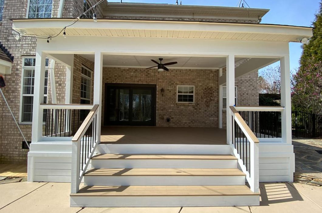a white-painted porch with stairs and a ceiling fan