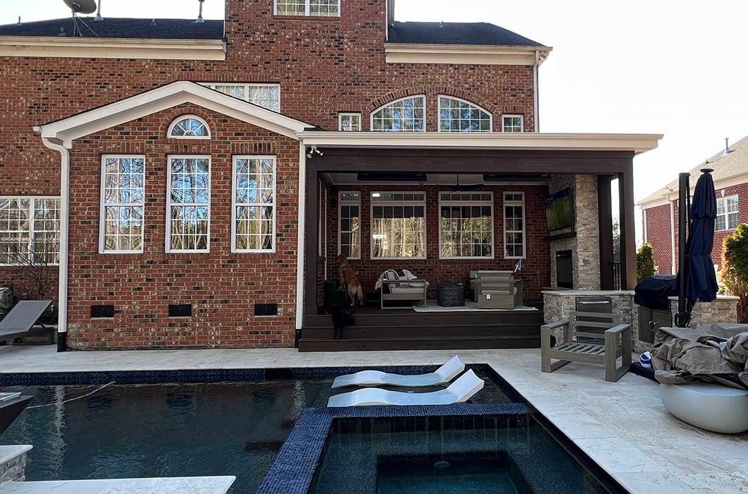 back porch that leads onto paver patio with a pool