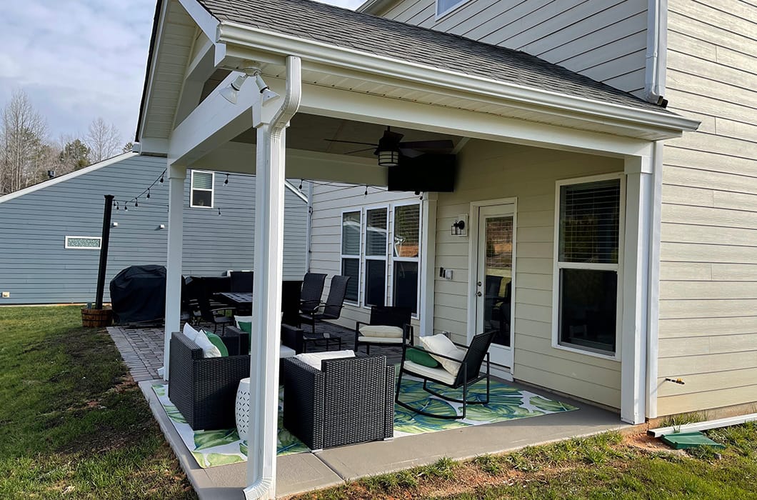 A covered stone patio with patio furniture and string lights