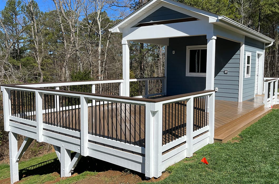 A stained wooden deck with white railing on a hill