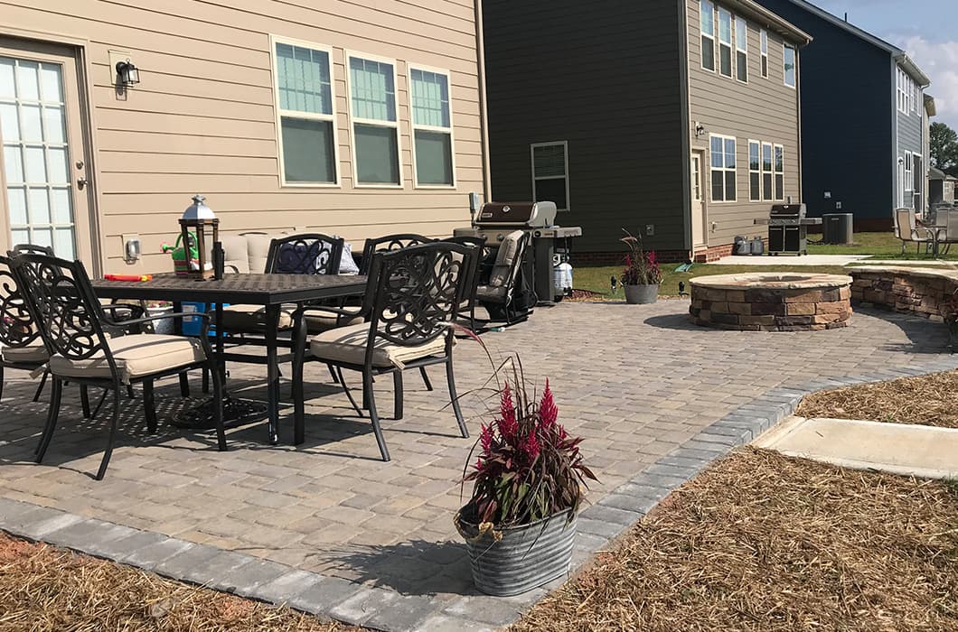 a brick patio with a fire pit and grill