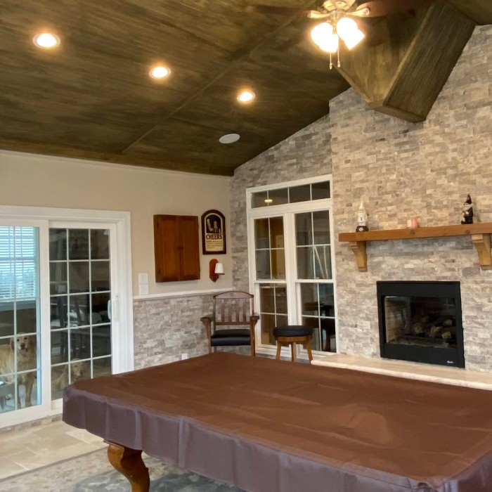 A three-season room with a fireplace and stone floors