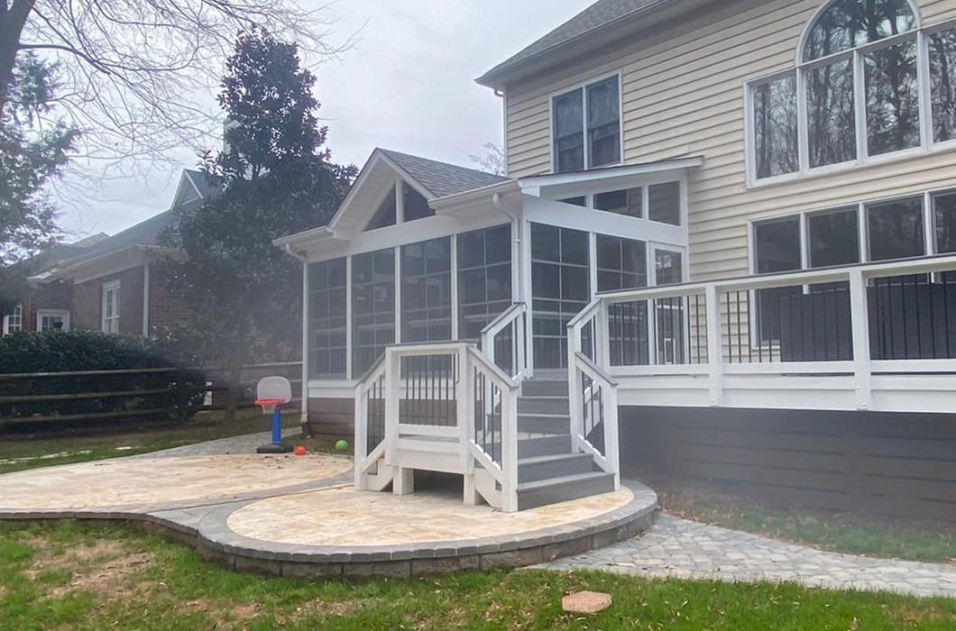 a three-season room the leads onto a deck with stairs and a patio