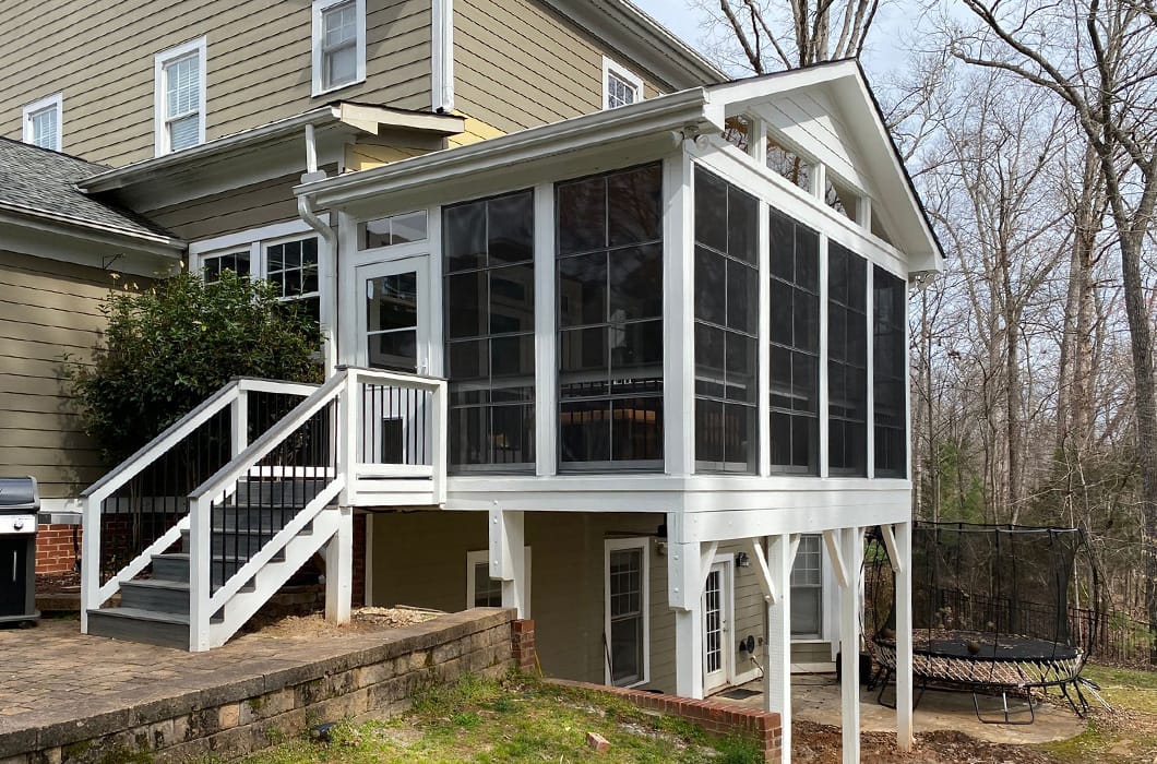 elevated three-season room with stairs leading onto a brick patio