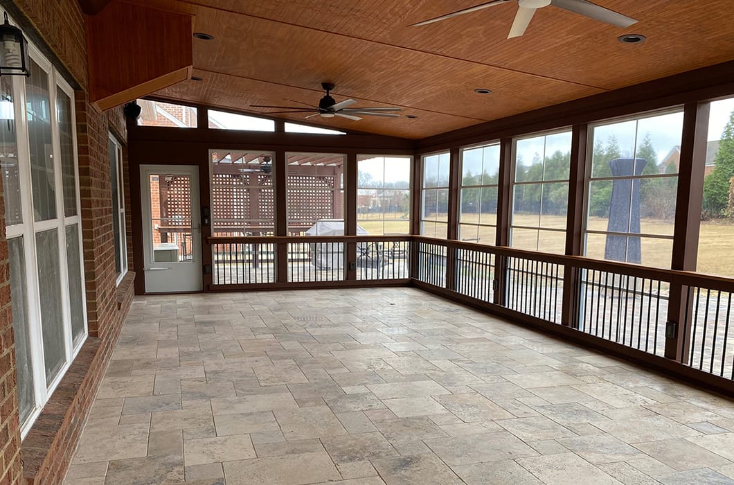 three-season room with a stone floor and dark wood railing