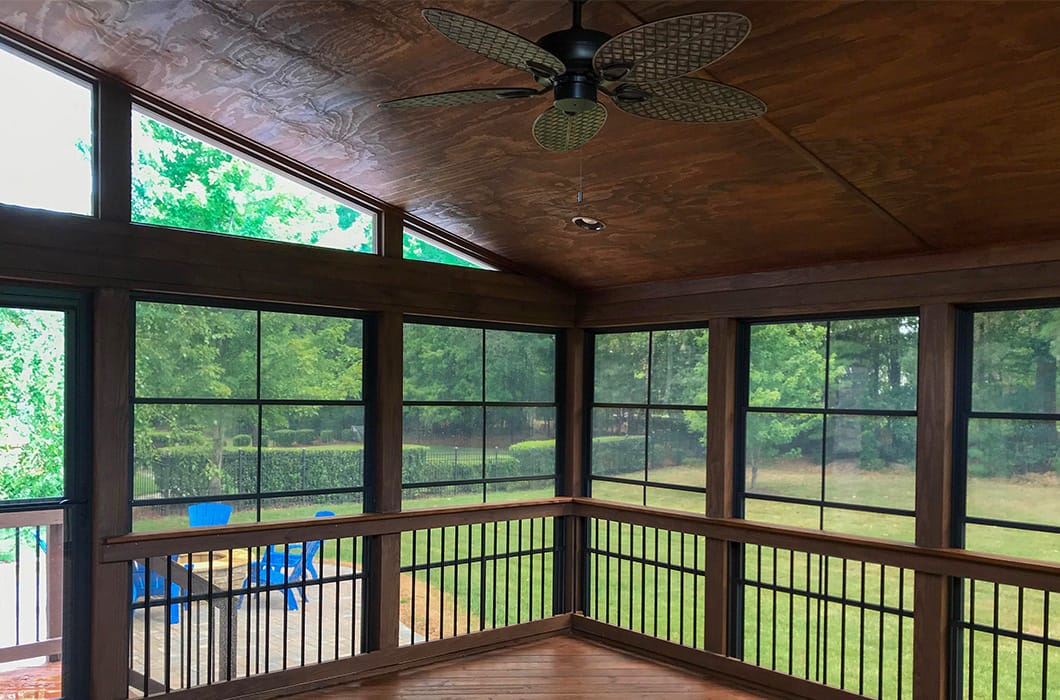 A three-season room with dark wood and a fan