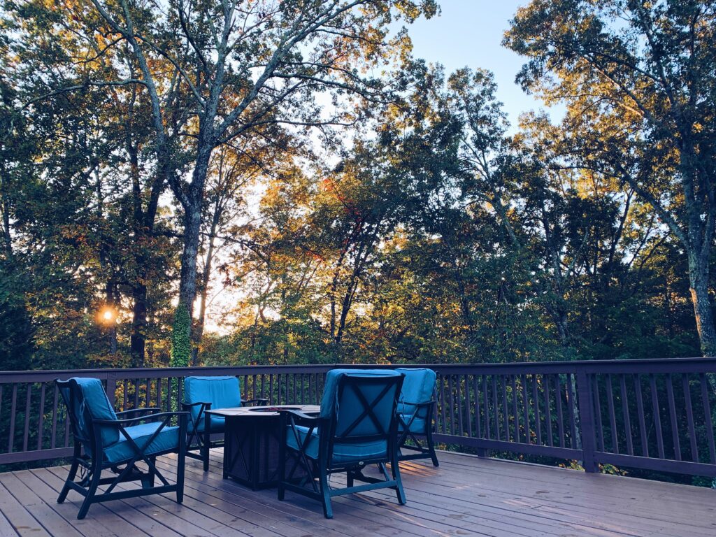 Deck with patio furniture;  fall foliage in the background.