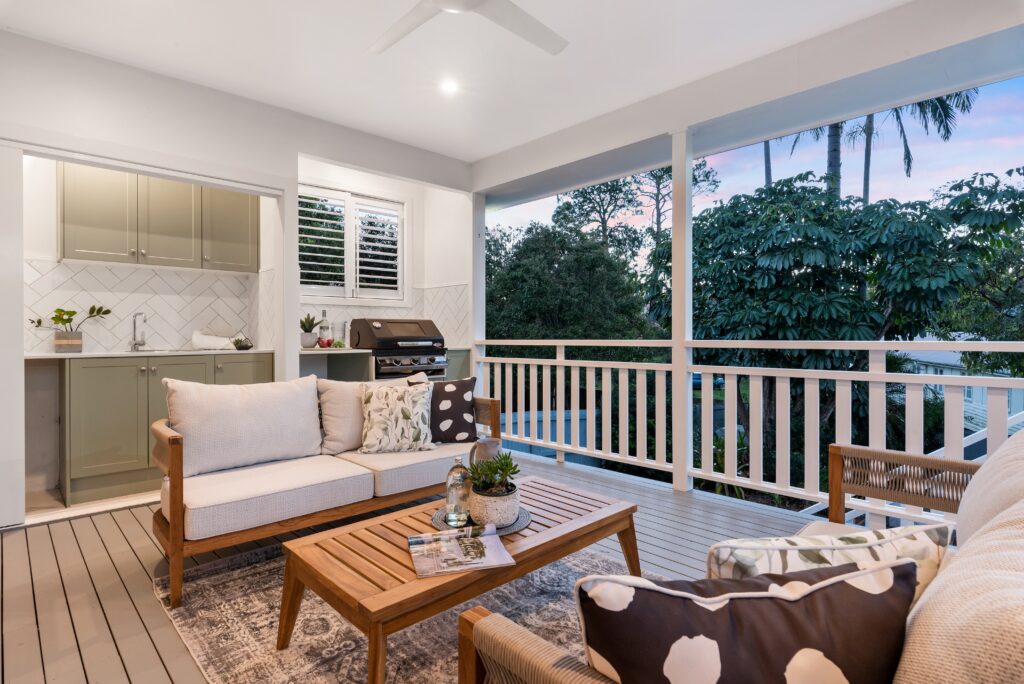 Outdoor covered deck with kitchen; complete with a sink, cabinetry, countertops, and a grill.